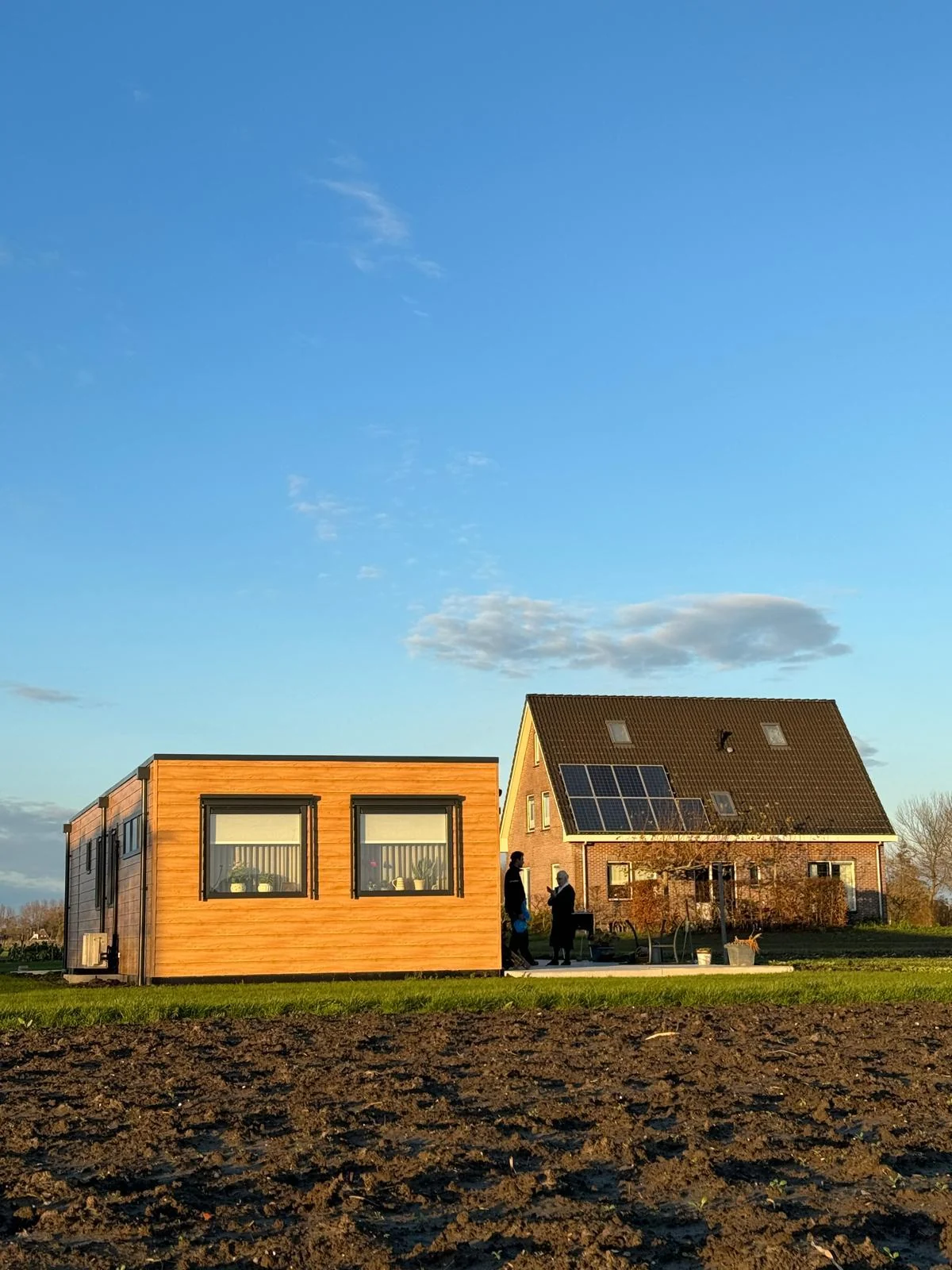 Mantelzorgwoning van BBS Systeembouw naast het woonhuis, in de avondzon